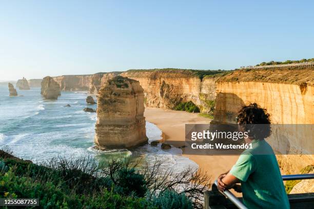 man standing on observation point at twelve apostles during sunset, victoria, australia - twelve apostles stock pictures, royalty-free photos & images