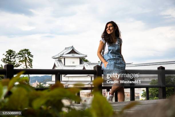 japan, ishikawa prefecture, kanazawa, portrait of young woman leaning on railing against kanazawa castle - kanazawa stock pictures, royalty-free photos & images