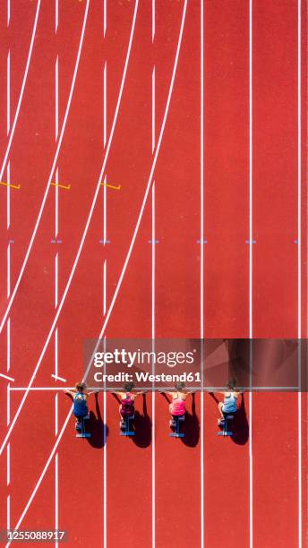 germany, baden-wurttemberg, winterbach, aerial view of female sprinters kneeling on starting line - linea di partenza attrezzatura sportiva foto e immagini stock