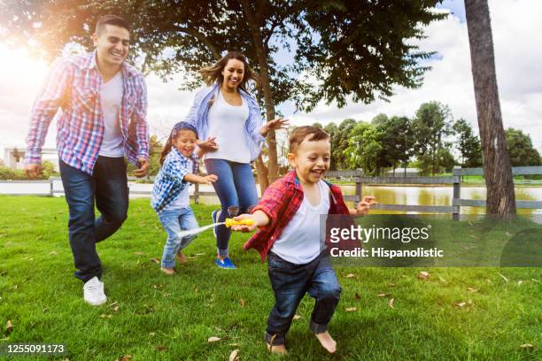 gelukkige jonge latijns-amerikaanse familie bij het park dat van een zonnig dagspel geniet - father son water park stockfoto's en -beelden