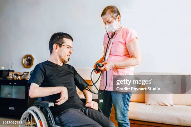 serious disabled young man at home with nurse - brain damage stock pictures, royalty-free photos & images
