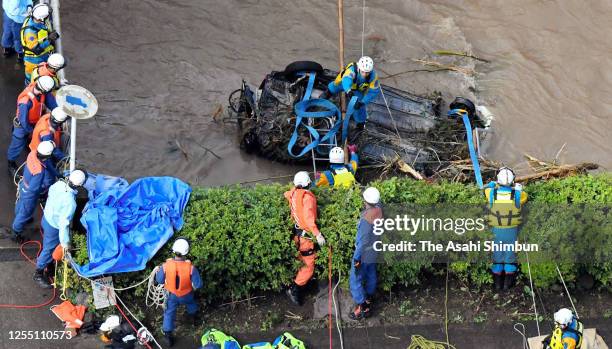 Police officers check the overturned car sunk in the river whether there is any victims inside after floodwater receded as heavy rains hit the area...