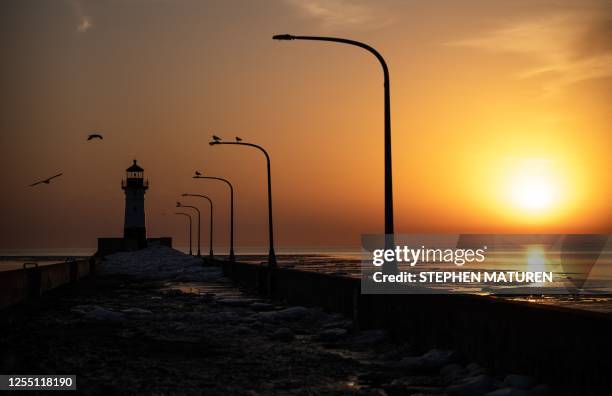 The sun rises over Lake Superior and the Duluth North Pier Lighthouse in Duluth, Minnesota, on April 13, 2023. In the far north of the United States,...