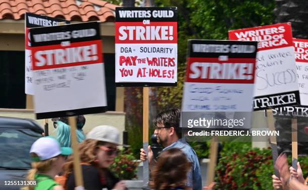 Writers hold signs while picketing in front of Paramount Studios in Los Angeles, California on May 15, 2023 as the strike by the Writers Guild of...