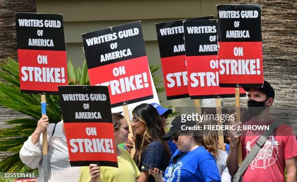 Writers hold signs while picketing in front of Paramount Studios in Los Angeles, California on May 15, 2023 as the strike by the Writers Guild of...