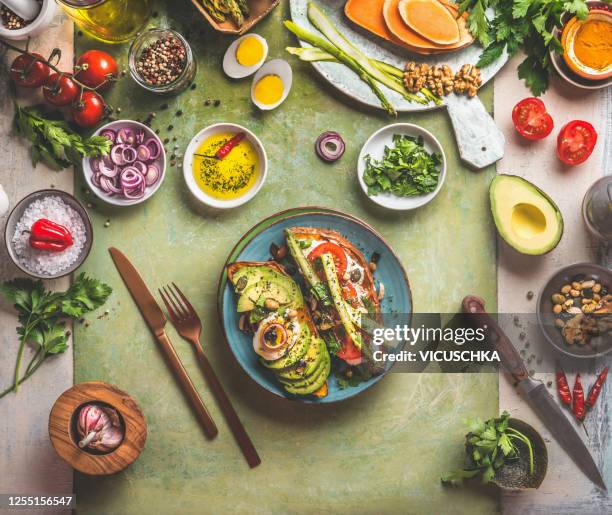 sweet potatoes sandwich avocado, egg, tomatoes and asparagus served on green kitchen table with ingredients: fresh vegetables, seasonings, olives oil and cutlery. - healthy dishes no people stock pictures, royalty-free photos & images