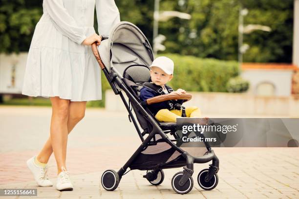 woman pushing baby stroller - mum pushing pram stock-fotos und bilder
