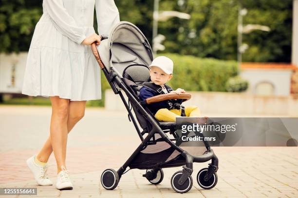 woman pushing baby stroller - femme poussette rue photos et images de collection