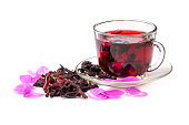 Hibiscus tea in glass cup among the rose petals and dry petals.