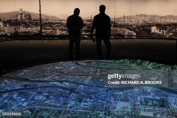 This photo taken on May 15, 2023 shows visitors looking at a display illustrating the devastation of the 1945 atomic bombing, at the Hiroshima Peace...