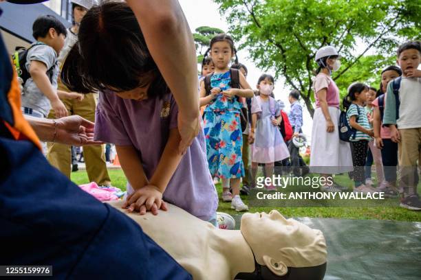 Child receives first aid instructions as she attends a civil defence drill at the government complex in Seoul on May 16, 2023.