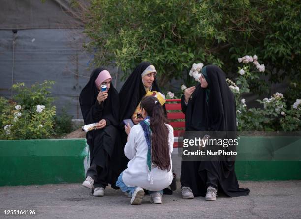 Young Iranian woman without wearing mandatory hijab sits next to her veiled friends while visiting International Book Fair at the Imam Khomeini grand...