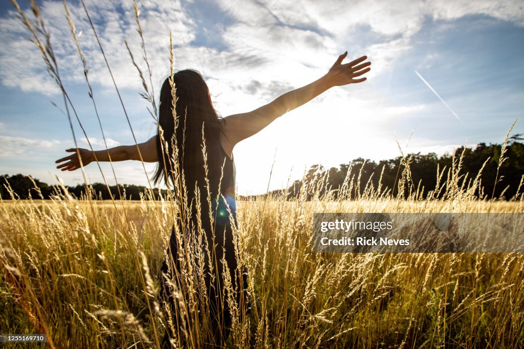 Japanese woman with open arms in field