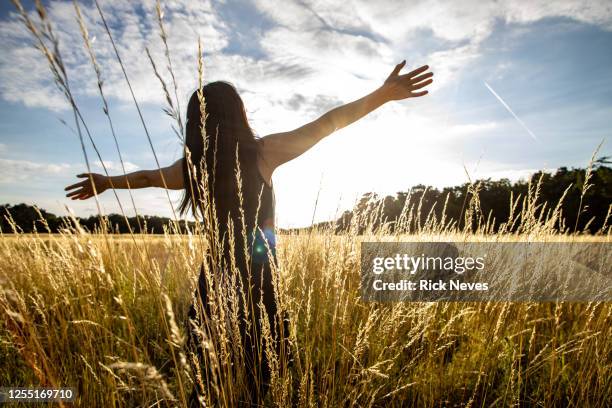 japanese woman with open arms in field - open flowers stock-fotos und bilder