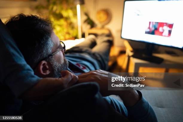 relaxed middle-aged man watching tv at night - man watching tv alone imagens e fotografias de stock