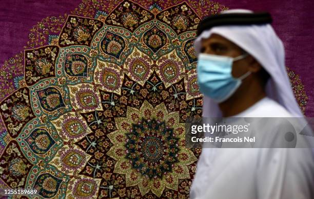 Vendor wearing a mask arranges carpets in his shop at Central Souq on July 09, 2020 in Sharjah, United Arab Emirates. The Coronavirus pandemic has...