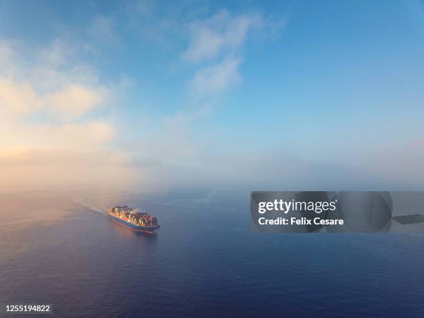 aerial view of a solo cargo ship on the move in open waters during sunrise. - marine marchande photos et images de collection