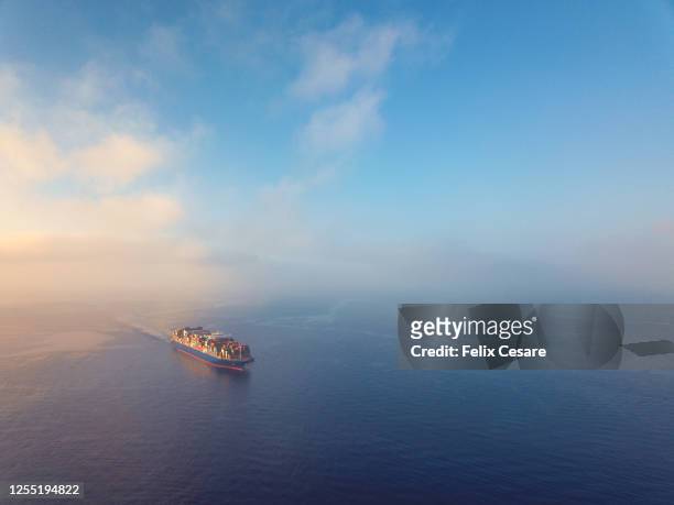aerial view of a solo cargo ship on the move in open waters during sunrise. - ship stock pictures, royalty-free photos & images