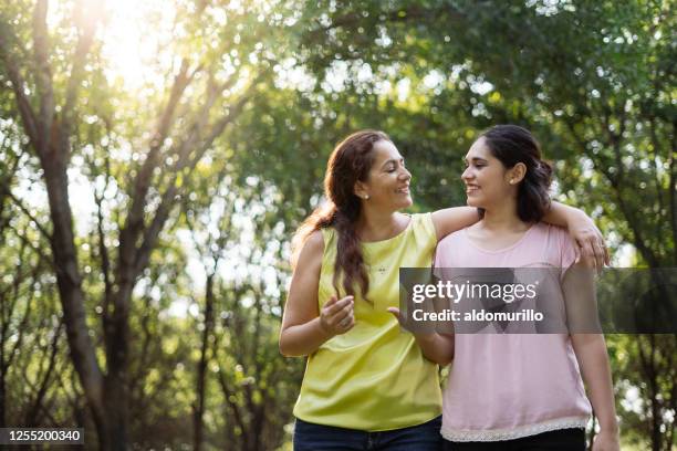 beautiful mother and daughter walking together outside - mother daughter hispanic stock pictures, royalty-free photos & images