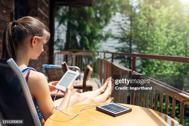 teenage girl reading ebook on cabin's balcony - solar panel isolated stock pictures, royalty-free photos & images