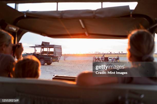 family in safari vehicle taking photographs of a safari picnic at sunset. - kalahari stock-fotos und bilder