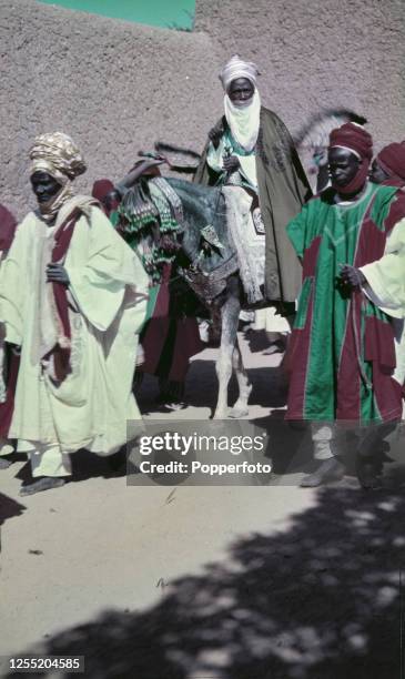 Muhammadu Sanusi I, the Emir of Kano, rides on a mule with palace courtiers in Kano, Nigeria in 1956. The Emir is due to meet with Queen Elizabeth II...