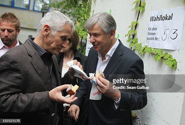 Berlin mayor and incumbent candidate of the German Social Democrats Klaus Wowereit and his partner Joern Kubicki taste cake offered to them by a...