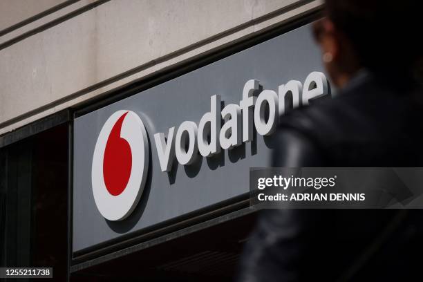 Pedestrian walks past a Vodafone store in central London on May 16, 2023. British mobile giant Vodafone is to axe 11,000 jobs over three years in the...