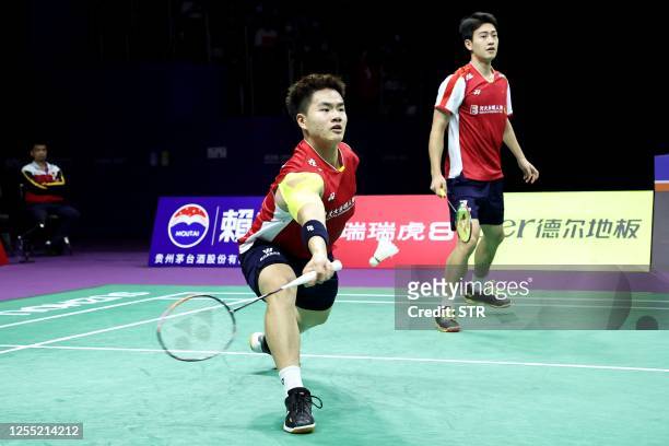Liang Weikeng of China hits a return beside partner Wang Chang during their men's doubles match with Jun Liang Andy Kwek and Loh Kean Hean of...