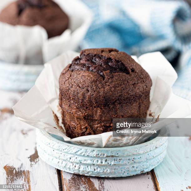 delicious homemade chocolate muffin on an old rustic wooden table with a blue knitted napkin - muffin stock pictures, royalty-free photos & images