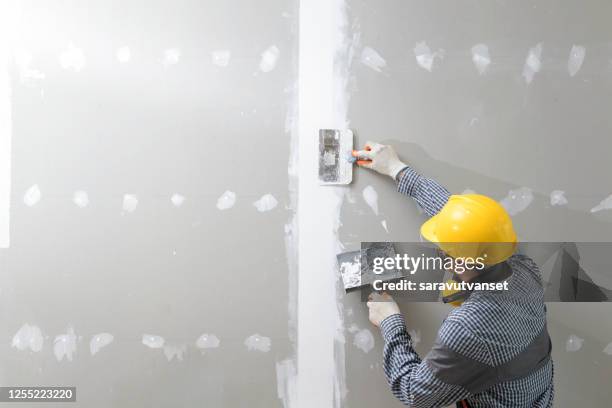rear view of a plasterer plastering walls - plasterer stock pictures, royalty-free photos & images
