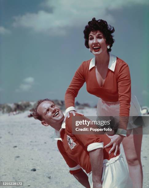 English singer Alma Cogan posed with English footballer and captain of Blackpool FC, Harry Johnston on a beach near Blackpool, England in August...