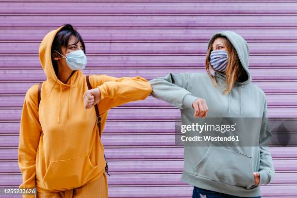 young woman wearing masks greeting with elbow - surgical mask stock-fotos und bilder