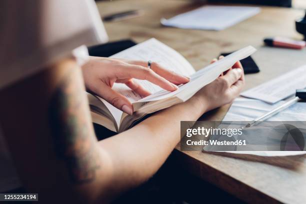 close-up of woman reading book at table in office - book close up stock-fotos und bilder