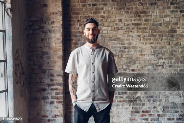 portrait of a stylish young man standing in loft - manga corta fotografías e imágenes de stock