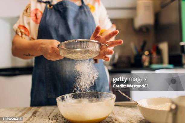 close-up of female baker sifting flour in batter on table at workshop - sieve stock pictures, royalty-free photos & images