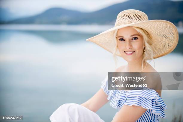 portrait of fashionable blond woman sitting on jetty at woerthersee, austria - kärnten am wörthersee stock pictures, royalty-free photos & images