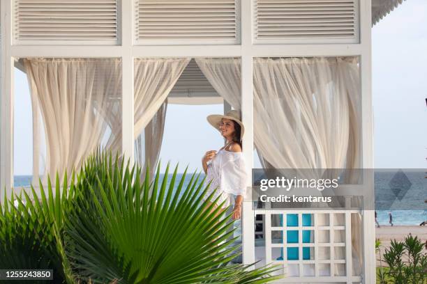 beautiful young girl is smiling and having a merry time on the beach at gazebo. cabana. arbor. - cabana stock pictures, royalty-free photos & images