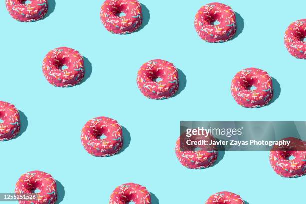 many pink donuts on turquoise colored background - sprinkles stock-fotos und bilder