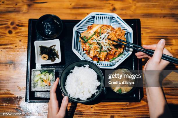overhead view of young asian woman enjoying freshly served traditional japanese meal set with miso soup and assorted appetizers in a japanese restaurant - asiatische küche stock-fotos und bilder