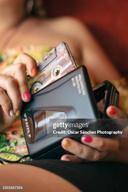 close-up of a woman inserting a cassette tape into a 80s personal player - música pop fotografías e imágenes de stock