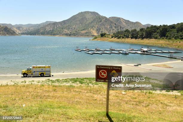 An emergency response vehicle sits in a parking lot near a danger sign warning visitor of hazards for swimming and wading at Lake Piru, where actress...