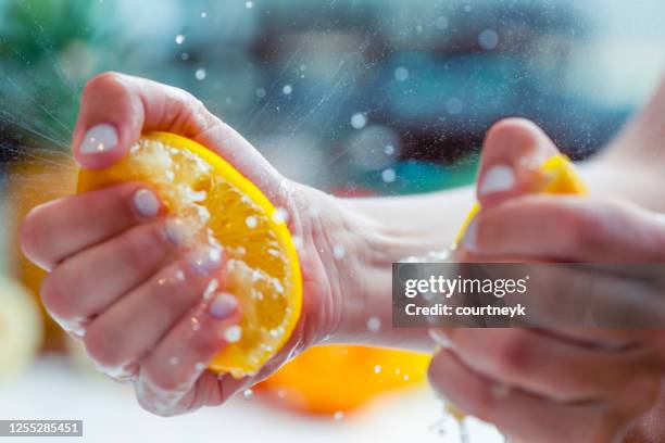 donna che stringe il succo da un limone. - squirting foto e immagini stock