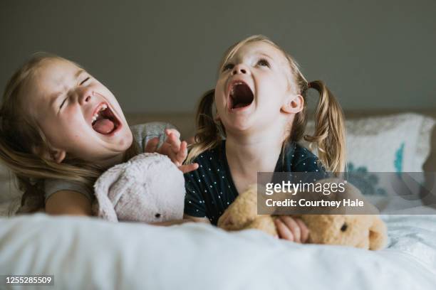 divertenti sorelle in età prescolare ed elementare urlano e cantano ad alta voce mentre suonano - gridare foto e immagini stock