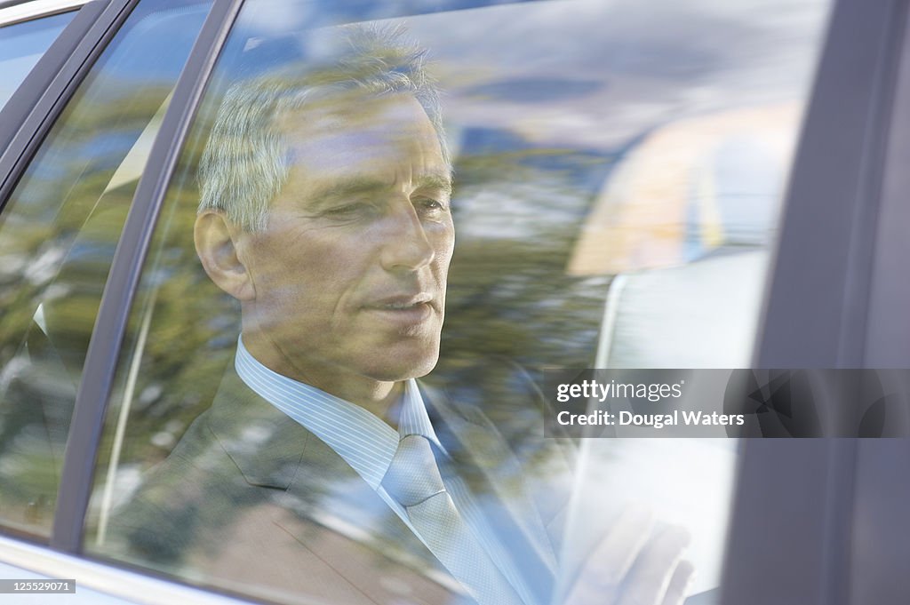 Business man in car using digital tablet.