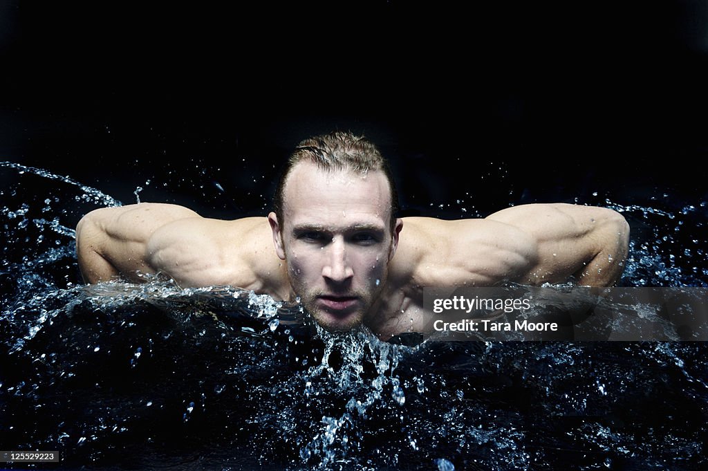 Muscle bound man swimming in water