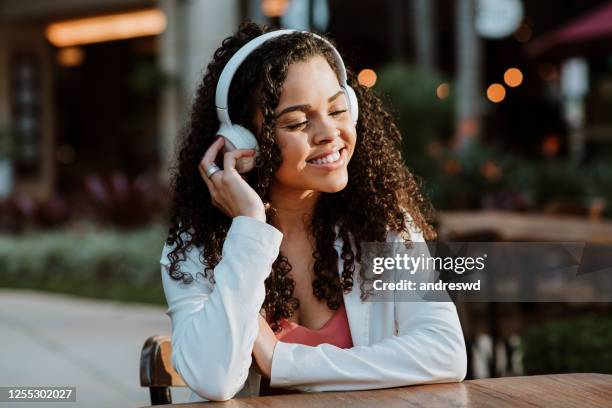 happy woman in bluetooth headphones relaxing outside the home - bluetooth headphones stock pictures, royalty-free photos & images