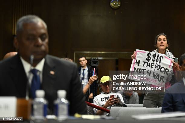 Code Pink demonstrator holds a sign as US Defense Secretary Lloyd Austin testifies during a Senate Appropriations Committee hearing on the 2024...