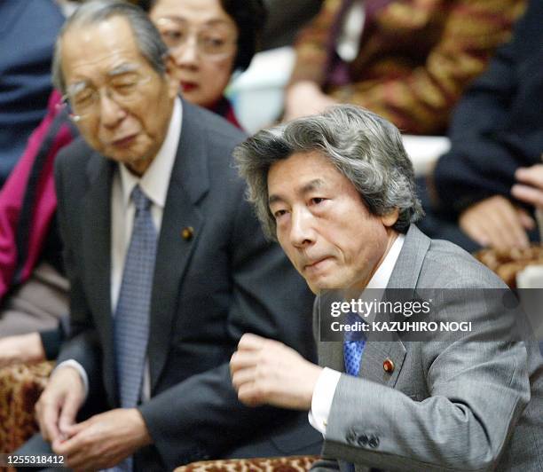 Japanese Prime Minister Junichiro Koizumi listens to a question while his cabinet member Finance Minister Masajuro Shiokawa looks on during a budget...