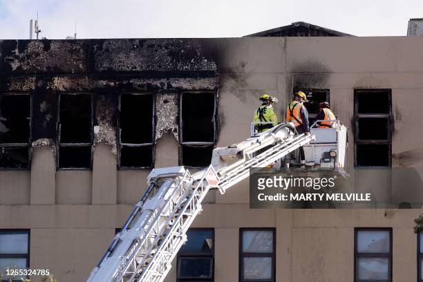 Firefighters inspect the Loafers Lodge hostel where a fire broke out a day earlier in the suburb of Newtown in Wellington on May 17, 2023. A fire...
